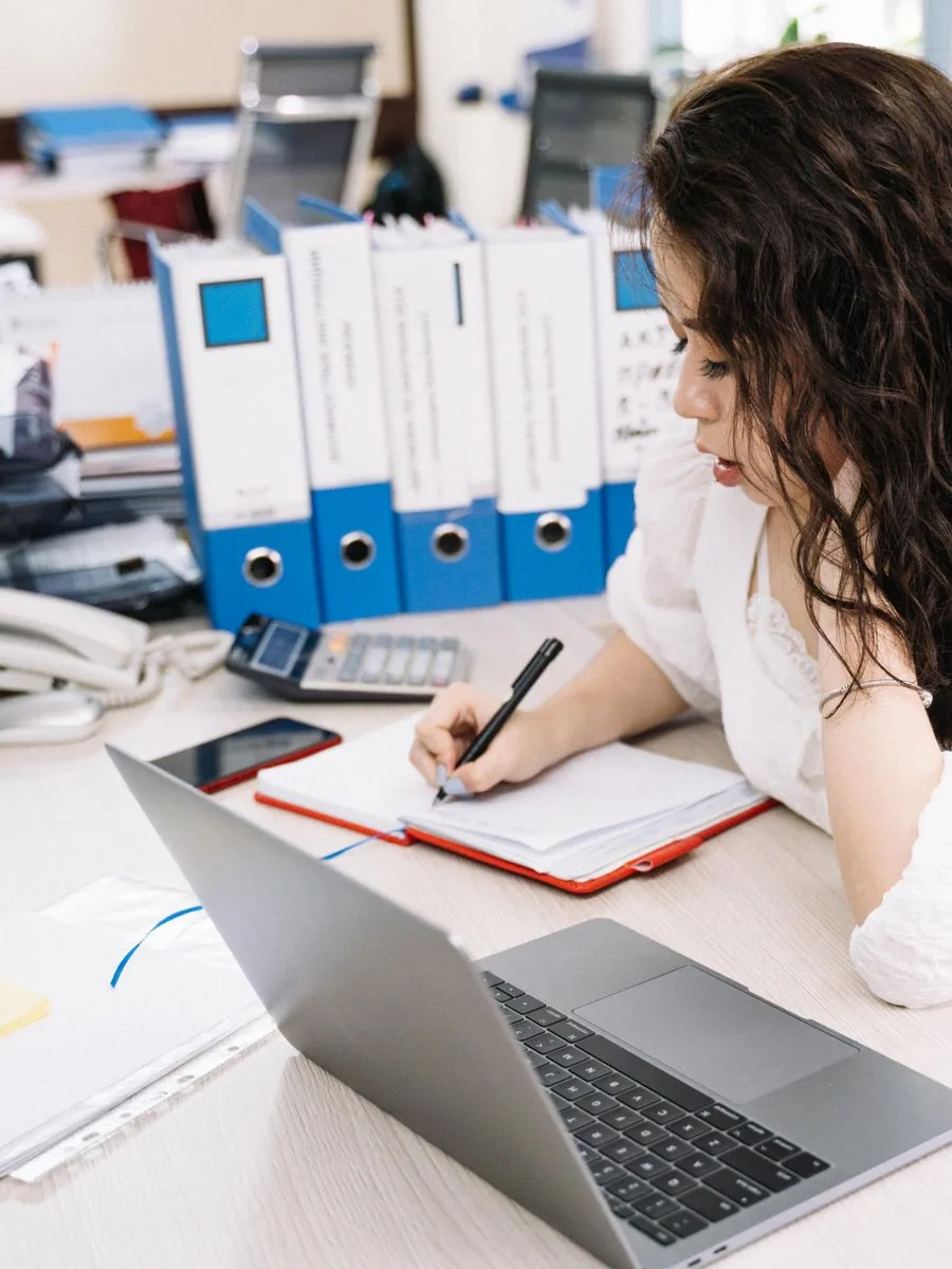 Creator at a desk analyzing engagement and working out their Instagram like-to-follower ratio with a laptop and notes