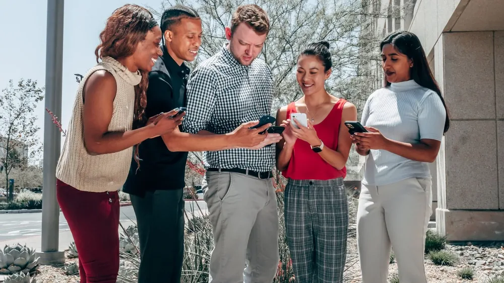 Group of creators and marketers sharing Instagram content on their phones, the kind of people who buy Instagram shares to amplify reach