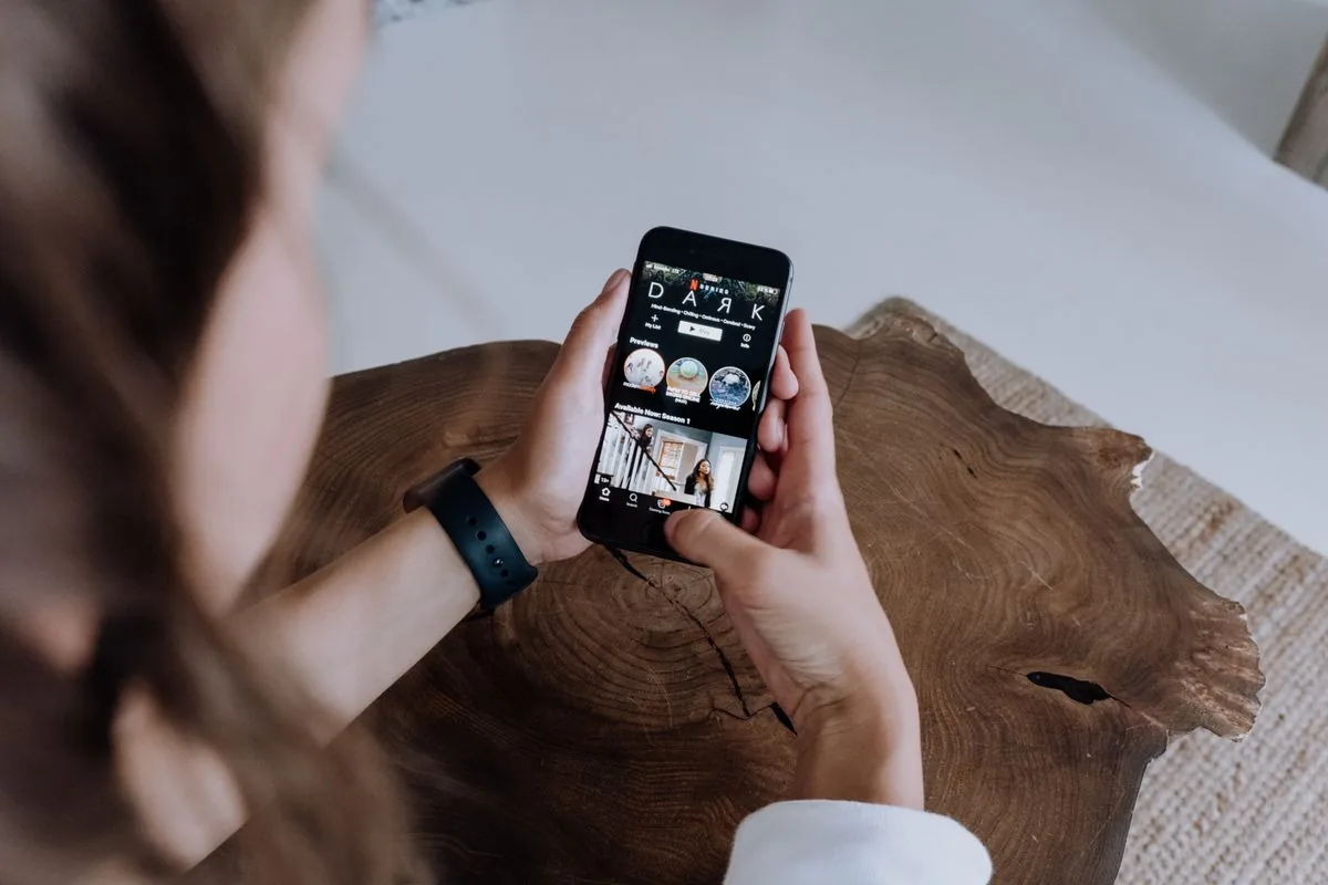 Person absorbed in watching short videos on a phone, showing that the TikTok For You Page is driven by watch time, not follower count