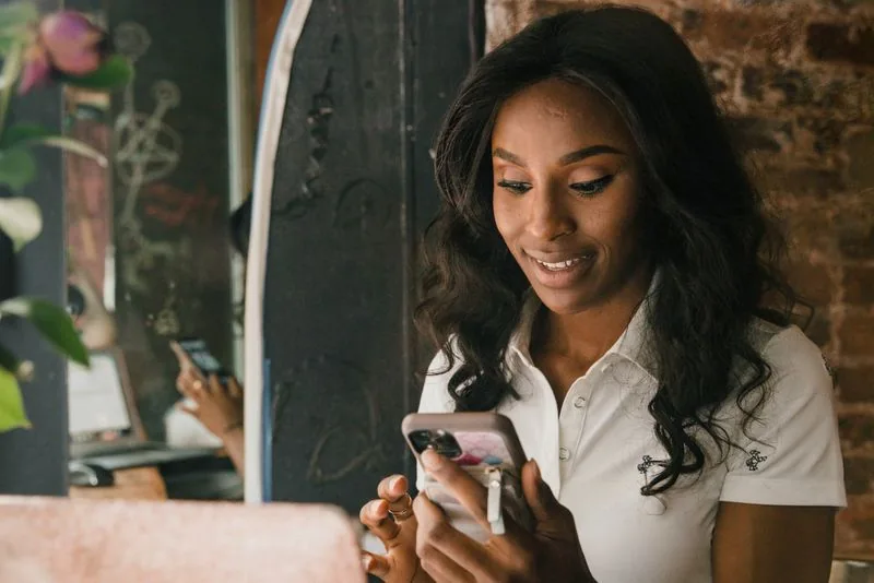 Creator smiling while engaging with comments on a phone, turning a like boost into real conversation and reach