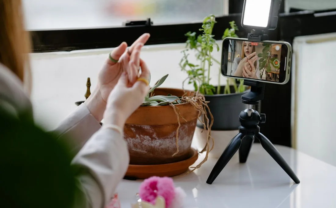 Creator filming a video with a phone on a tripod, making content with a hook worth sending and a clear prompt to share or Repost