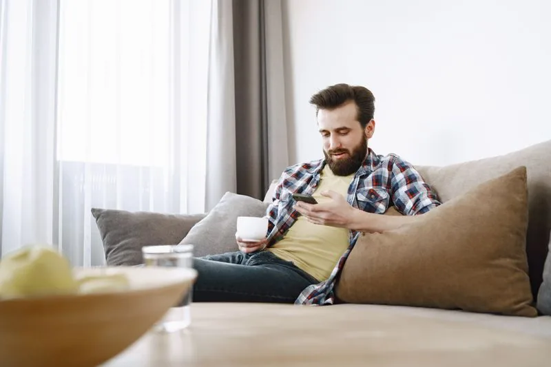 Person relaxing calmly with a phone and coffee, illustrating a safe, password-free way to buy TikTok views using only a public video URL