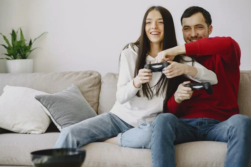Friends playing games and laughing together on a couch, showing the real Twitch community built by converting a bought follower boost into genuine fans
