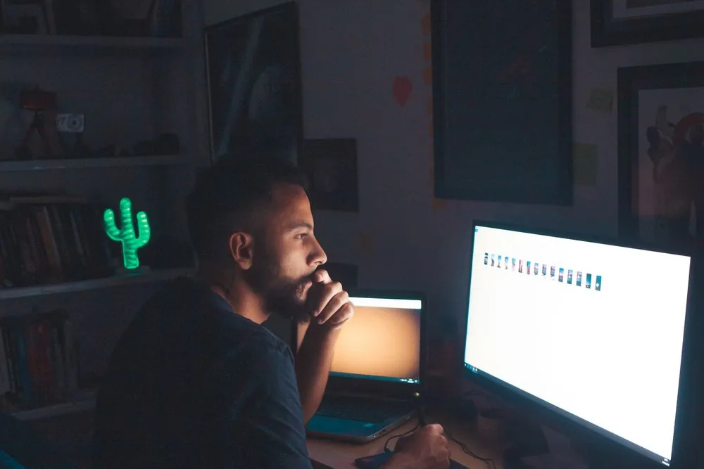 Person watching a stream on a screen in a dark room, showing that Twitch discovery is driven by live viewers, not follower count