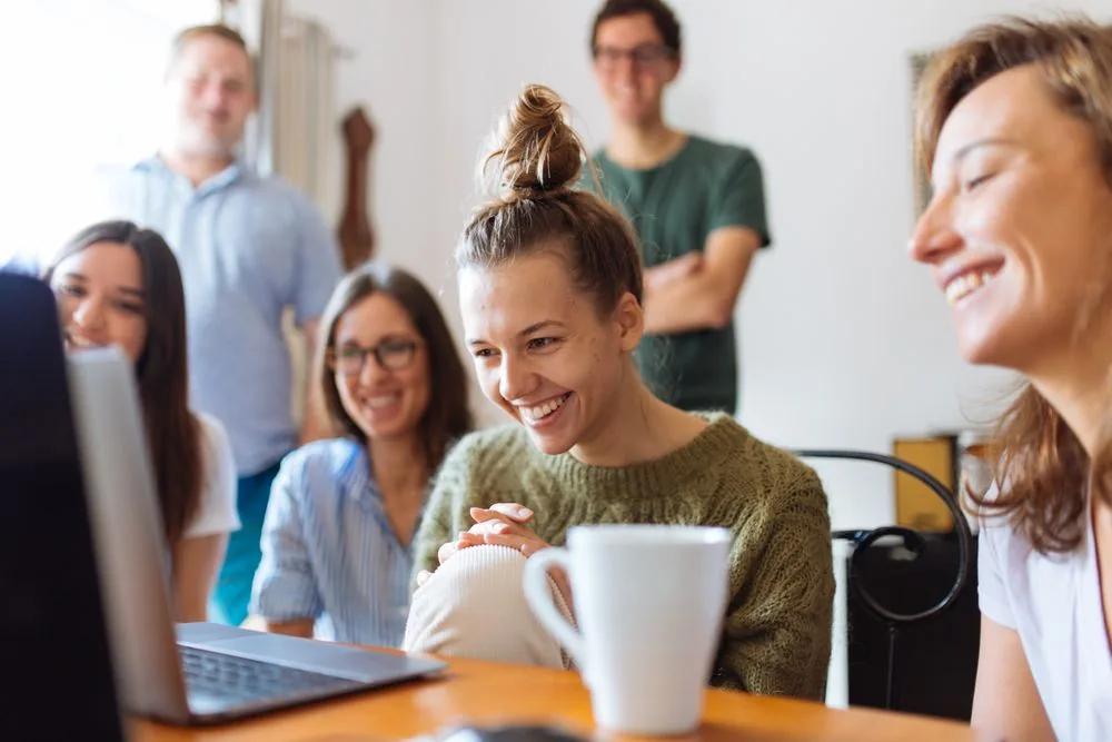 A group of people watching content together on a laptop, showing that Twitch discovery runs on live viewers while view counts work as social proof