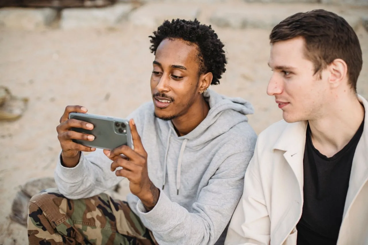 Two friends watching a YouTube video together on one phone, the real off-platform audience a genuine share reaches
