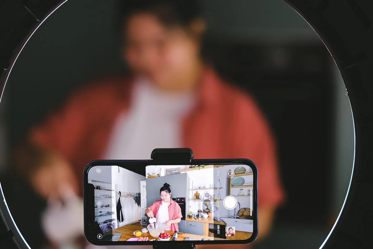 A creator recording a video with a phone and ring light, making the shareable content that turns bought YouTube shares into organic reach